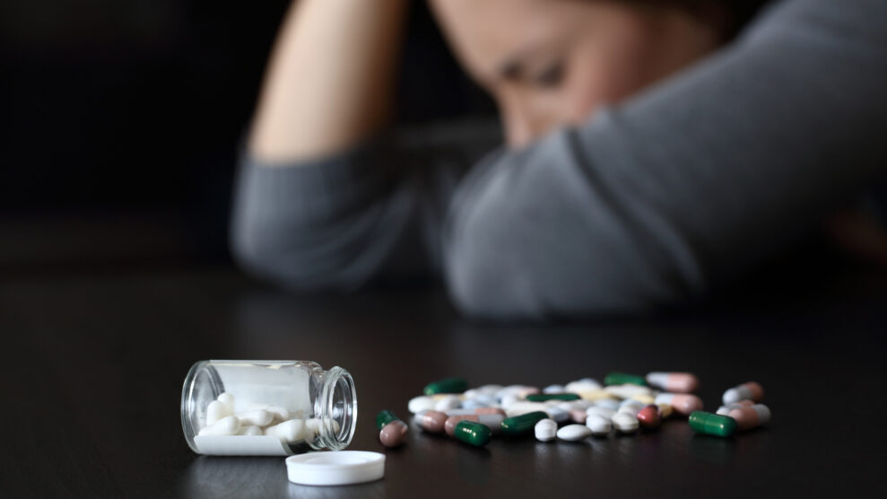 Depressed woman beside a lot of pills